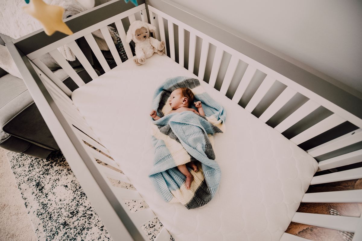A parent reading a picture book to a baby in soft lamplight before bed in a cozy nursery