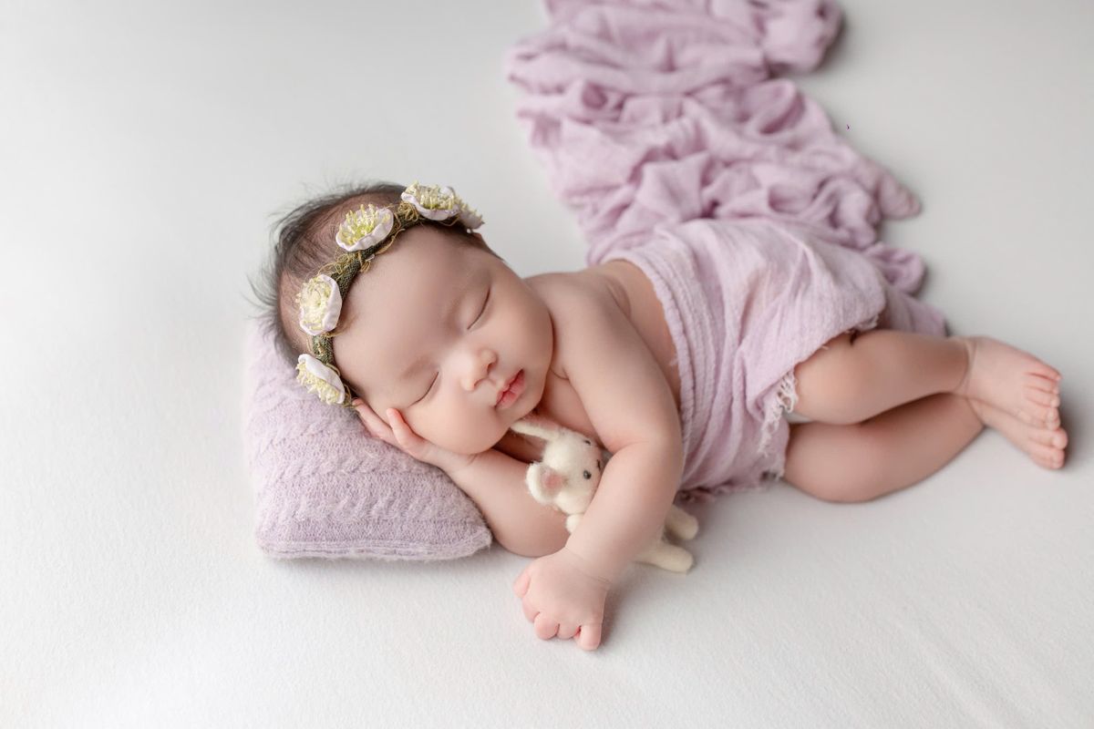A baby standing and holding the rail of their crib in a dim nursery