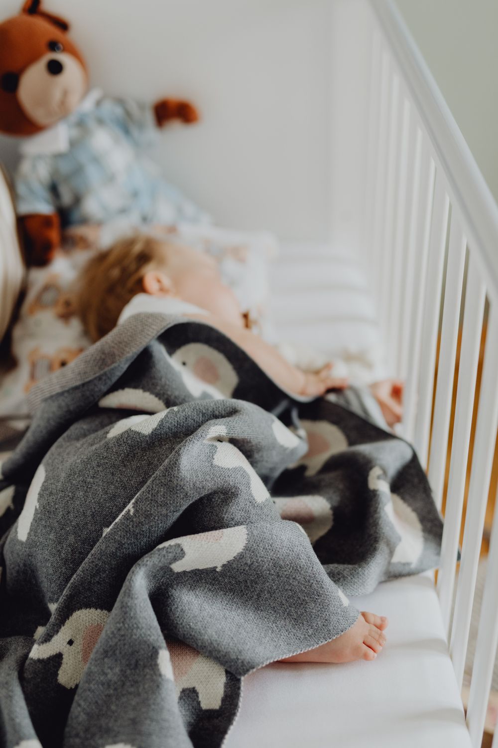 Calm sleepy baby with heavy eyelids being lowered into a crib on their back