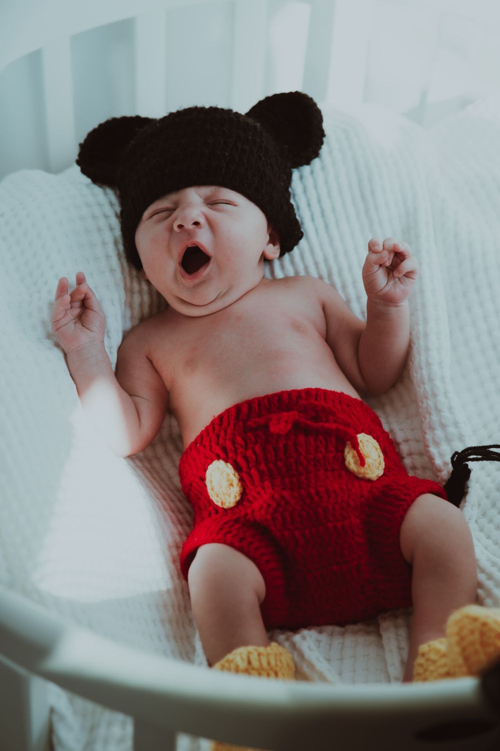 A parent sitting in a dimly lit nursery holding a baby during a middle-of-the-night feed
