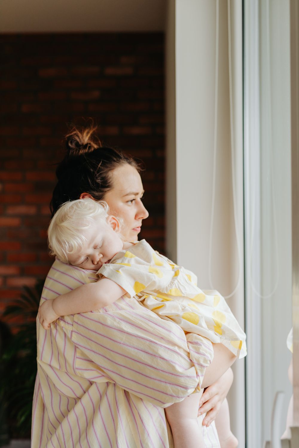 A parent holding a baby while glancing at a phone to check the last feed and nap
