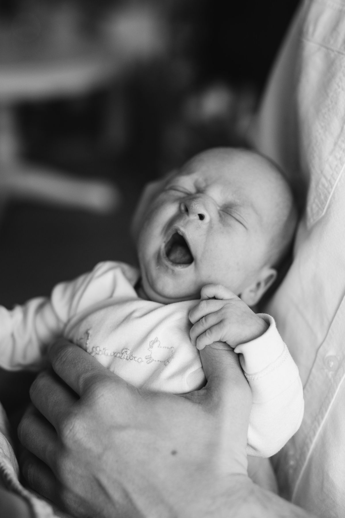 A parent gently lowering a drowsy baby into a crib in a softly lit nursery