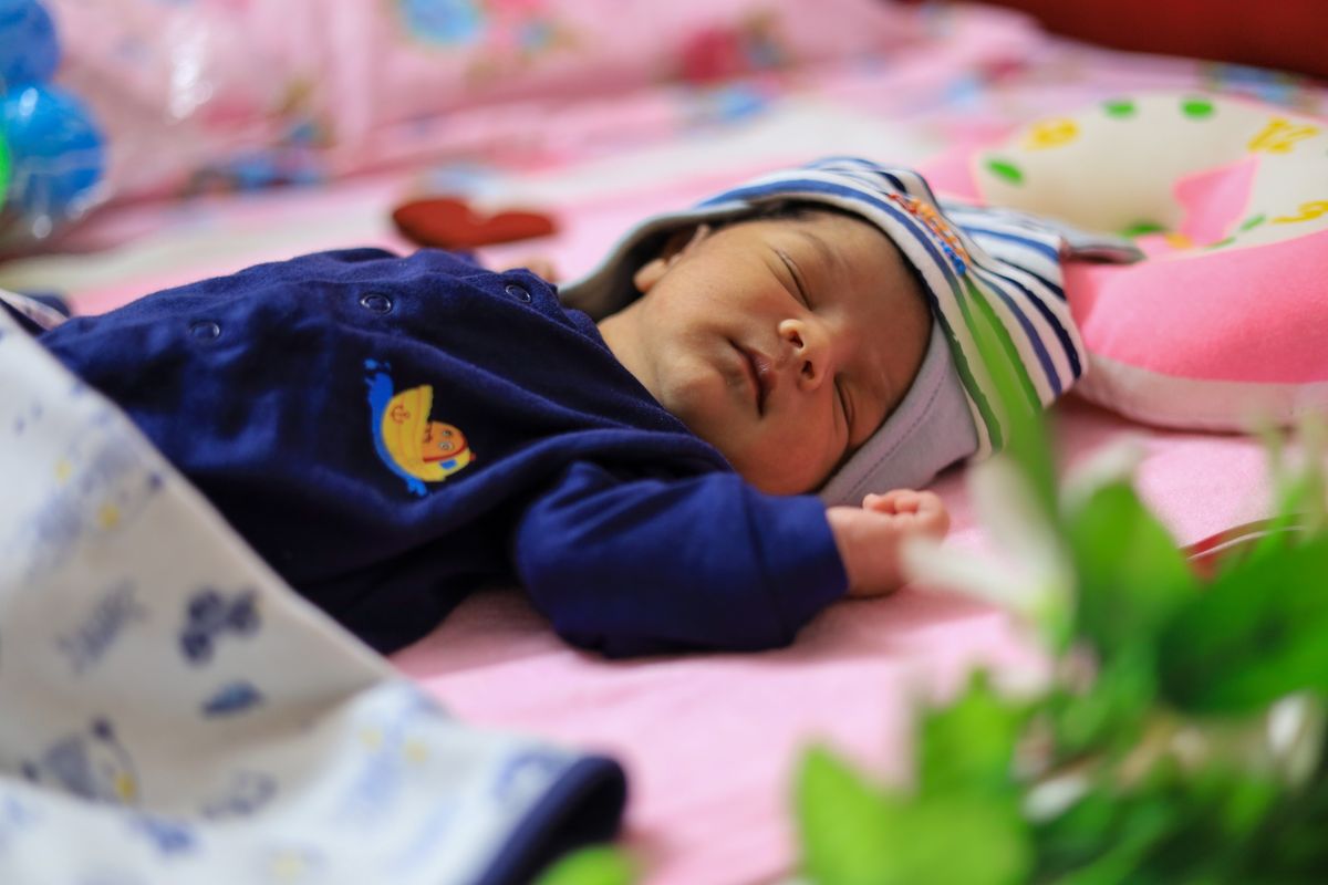 A nursery with a room thermometer showing a comfortable temperature and a baby sleeping in a sleep sack