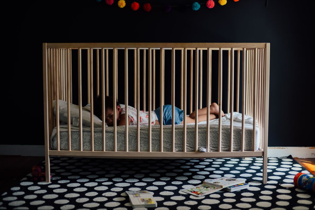 A calm baby sleeping on their back in a bare bassinet with a fitted sheet and no loose bedding
