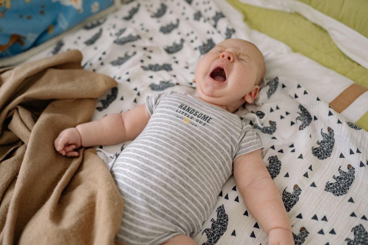 A baby napping peacefully on their back in a dim, cozy nursery