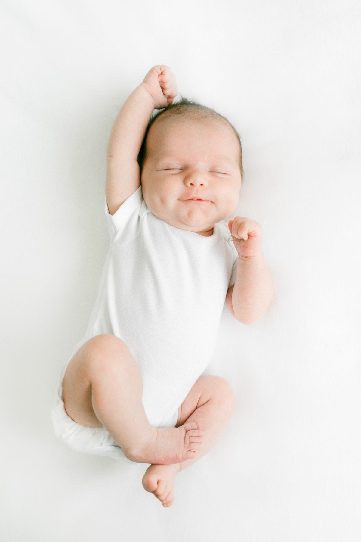 Newborn baby stretching arms up while waking, illustrating wake windows